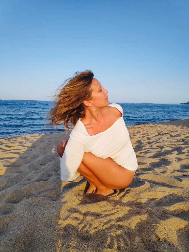 Dr. michelle goodrick on the beach in pasasana santosha